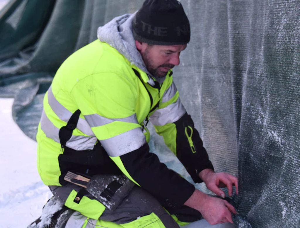 Man monterar skuggväv för att skydda växter under vintern.